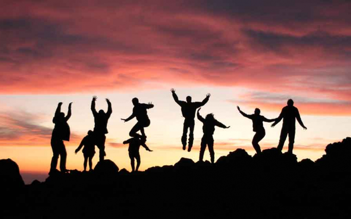 silhouette of teens jumping into the air at sunset